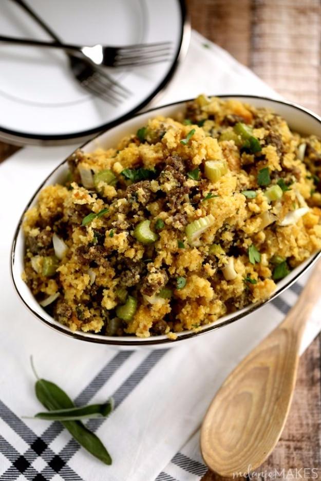 Golden cornbread stuffing with browned sausage, vegetables, herbs and a wooden spoon in a white oval bowl