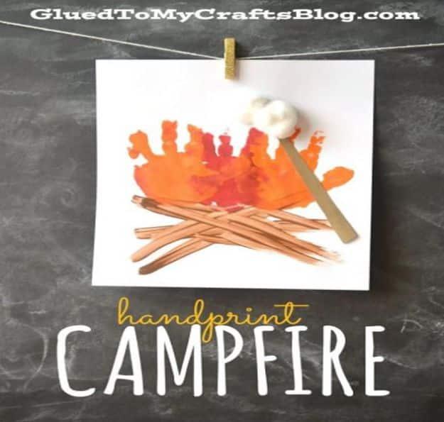 Handprint campfire with orange and red handprints as flames and craft stick logs, clipped to a string on a chalkboard