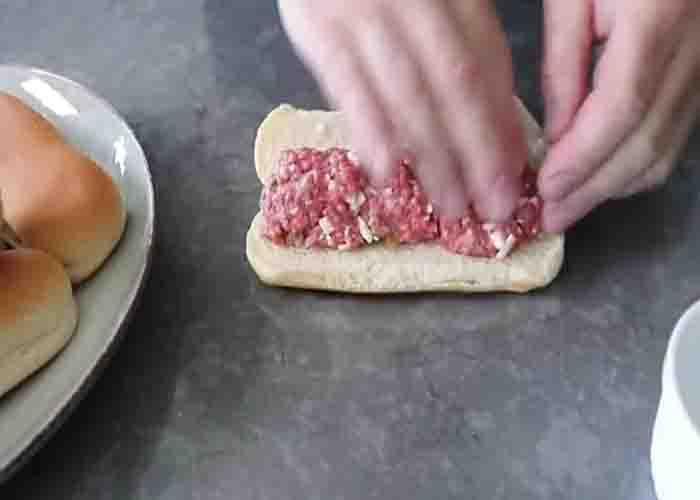 Adding the ground beef to the hotdog buns