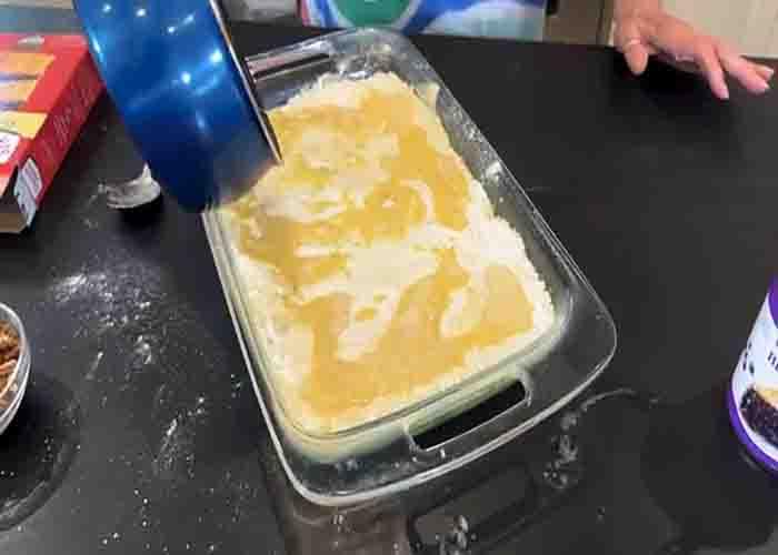 Spreading the butter all over the top of the pineapple blueberry crunch cake