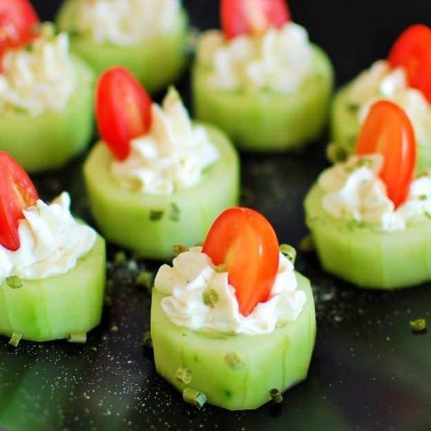Stuffed cucumber bites, hollowed cucumber rounds piped with herbed cream cheese and topped with cherry tomatoes