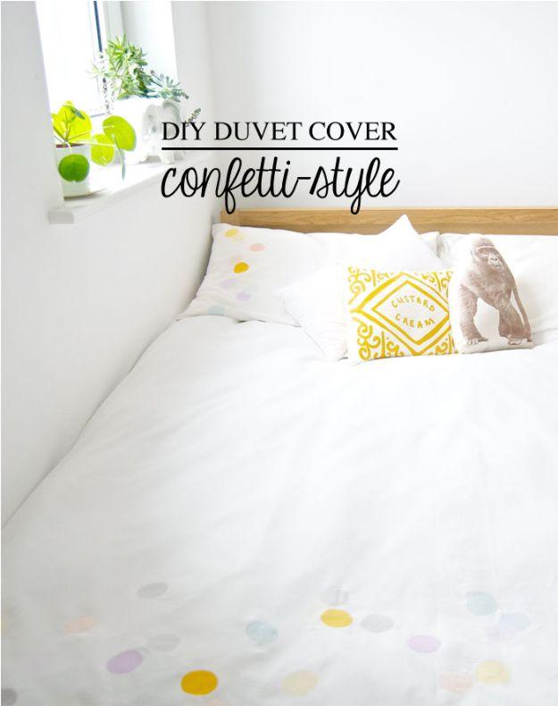 White DIY duvet cover hand painted with scattered pastel confetti dots on a bed under a bright window