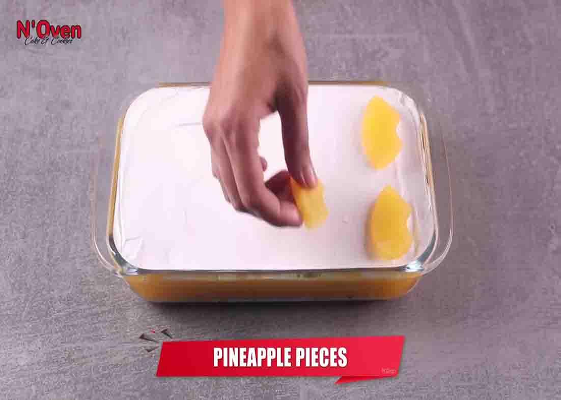Adding pineapple slices on top of the pineapple pudding