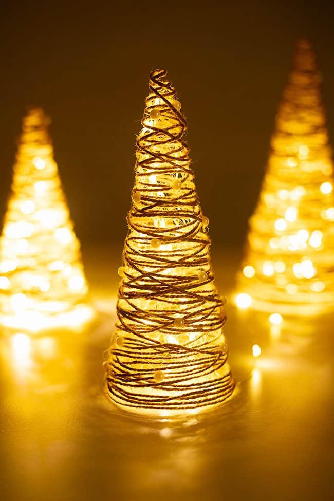 Three twine string Christmas trees glowing from white LED lights inside, dotted with pearl stickers on a dark table
