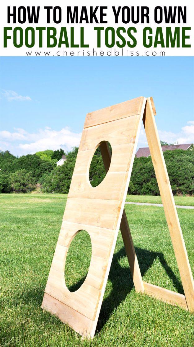 DIY football toss game made from cedar boards with two cut-out target holes, standing folded open on a green lawn