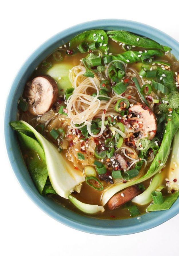 Ginger garlic noodle soup in a pale blue bowl with bok choy, mushrooms, rice noodles, scallions and chili