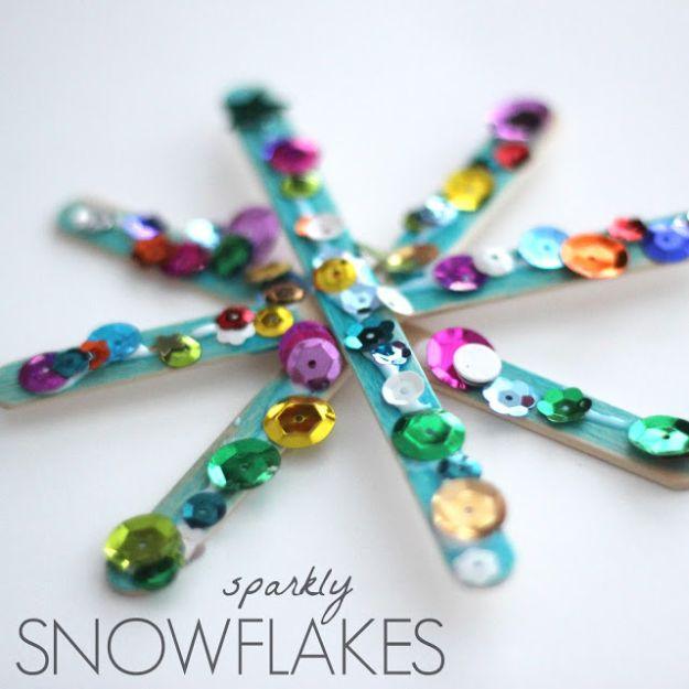 Popsicle stick snowflake painted teal and covered with multicolored sequins, pin graphic reading sparkly snowflakes