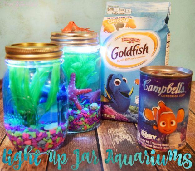 DIY aquarium jars lit blue and green with plastic sea creatures and coloured gravel on a wooden table