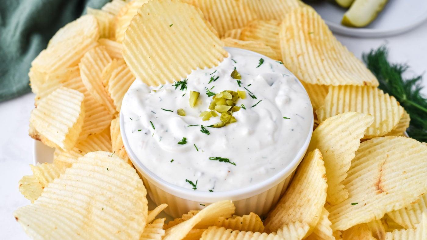 Dill pickle dip in a bowl with chopped dill pickles and fresh dill stirred through a creamy white base