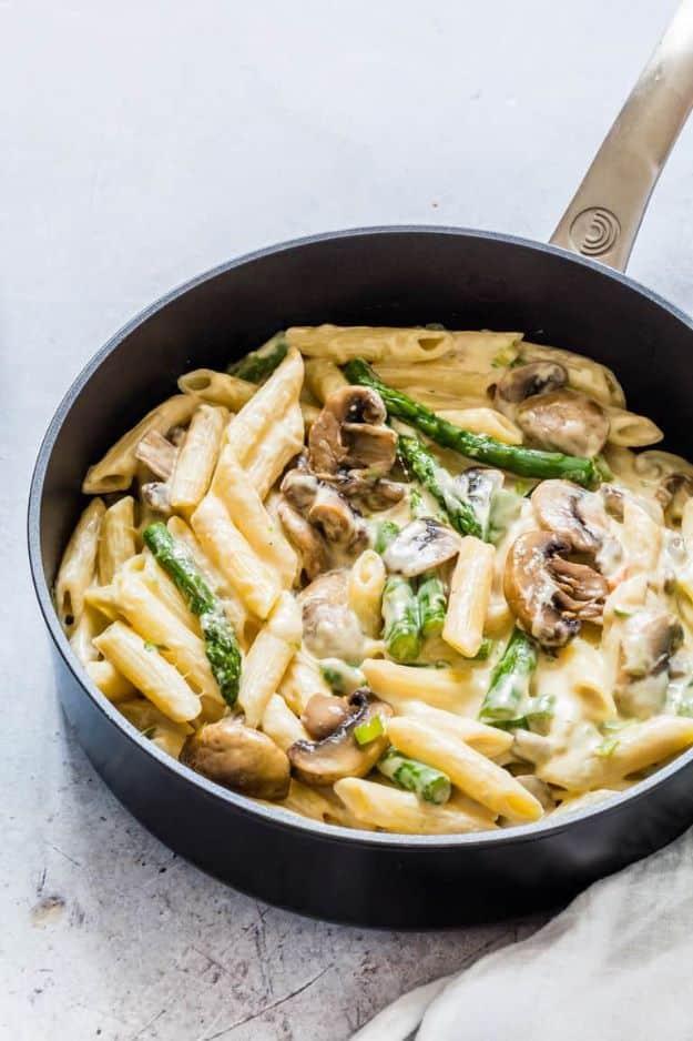 Mushroom asparagus pasta in a black pan with penne, sliced mushrooms and asparagus in a creamy sauce