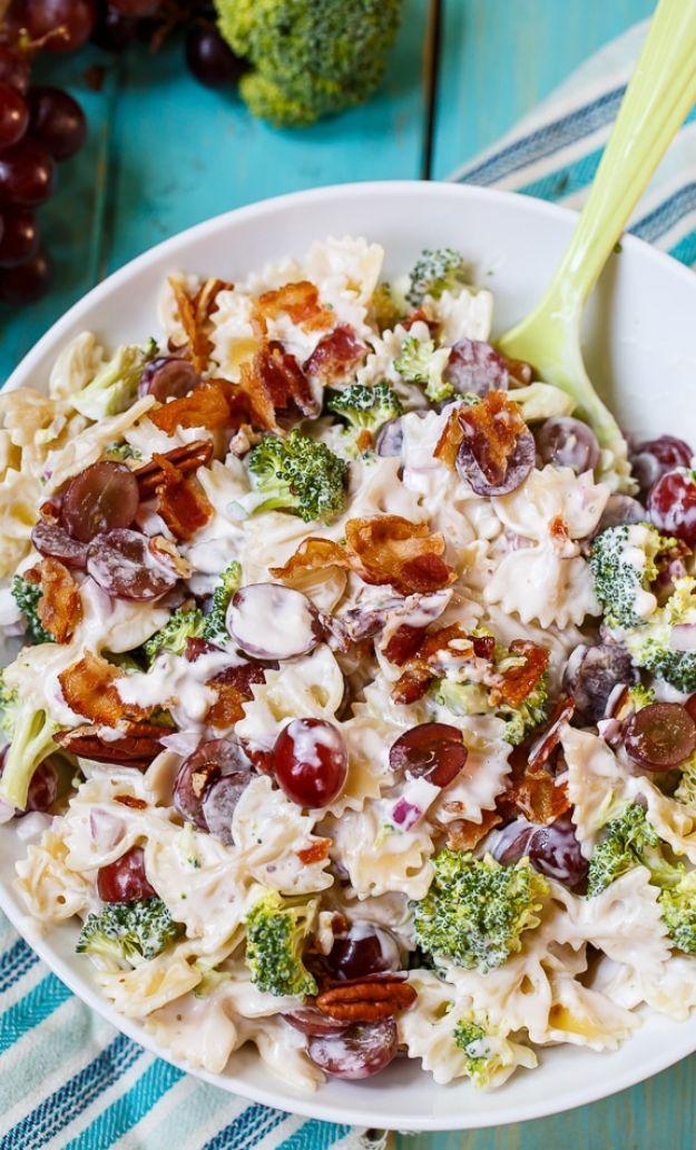 Broccoli grape and pasta salad with farfalle, chopped broccoli, red grapes and bacon in a white bowl