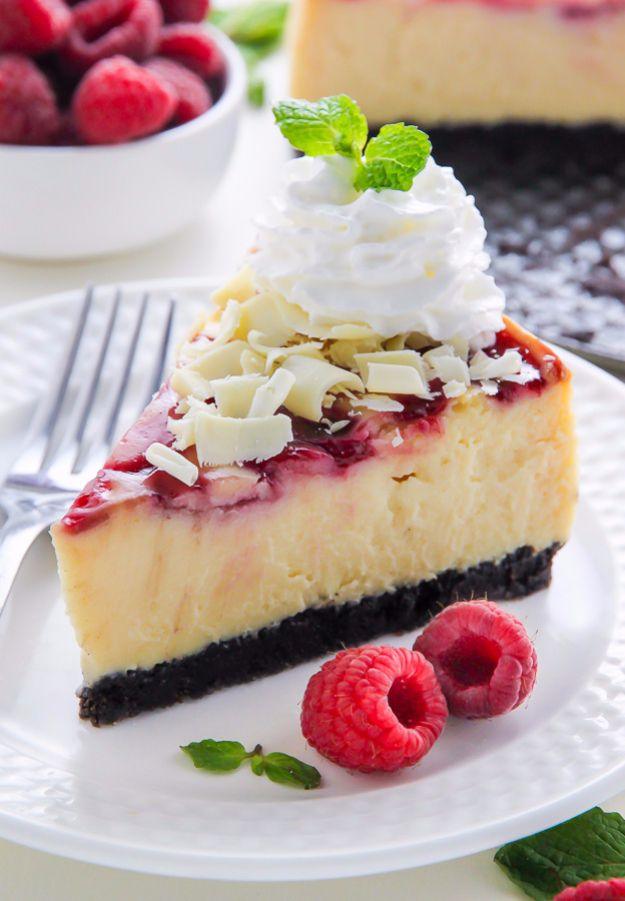 White chocolate raspberry cheesecake slice with a pink swirl top and dark Oreo crust, fresh raspberries beside
