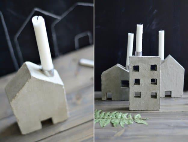 House and building candle concrete holders, small cast cement houses and a chimneyed factory holding white taper candles