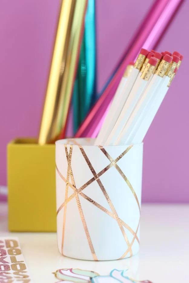 A tin can painted white and banded with gold foil, filled with pencils, one of the cheap things to make and sell