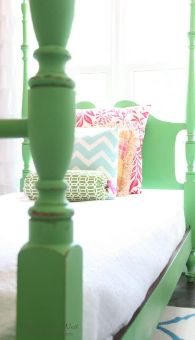 Bright green chalk painted four poster bed frame with turned posts, made up with white bedding and bright pillows