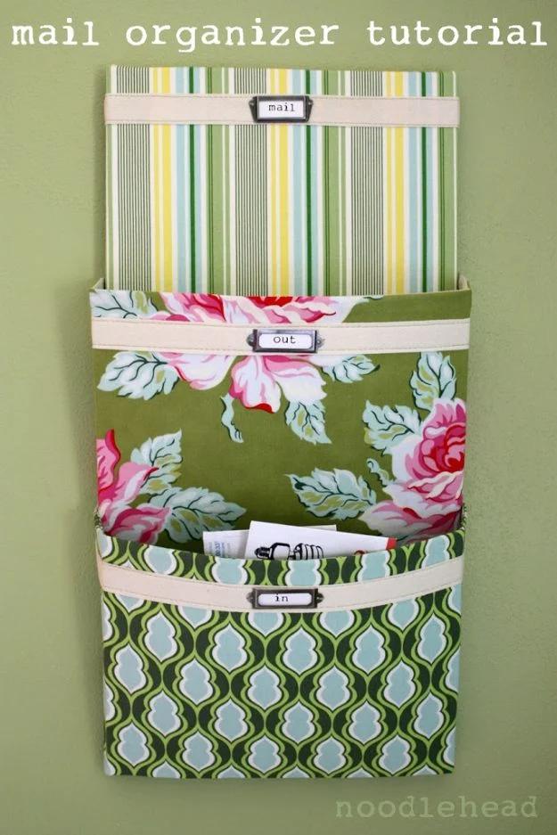 Green striped and floral fabric mail organizer with three labelled pockets mounted on canvas against a sage green wall