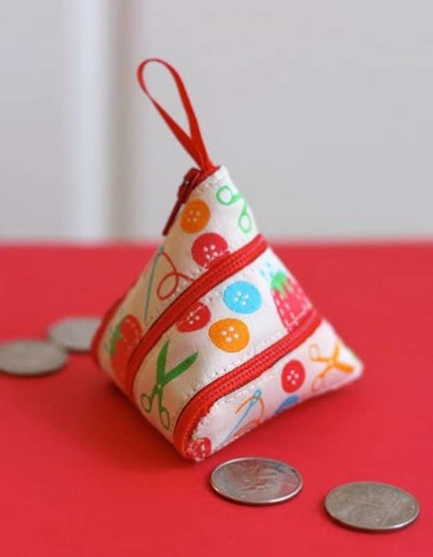 Small triangular zipper coin purse in button and scissors print fabric with a red zipper and tab beside loose coins