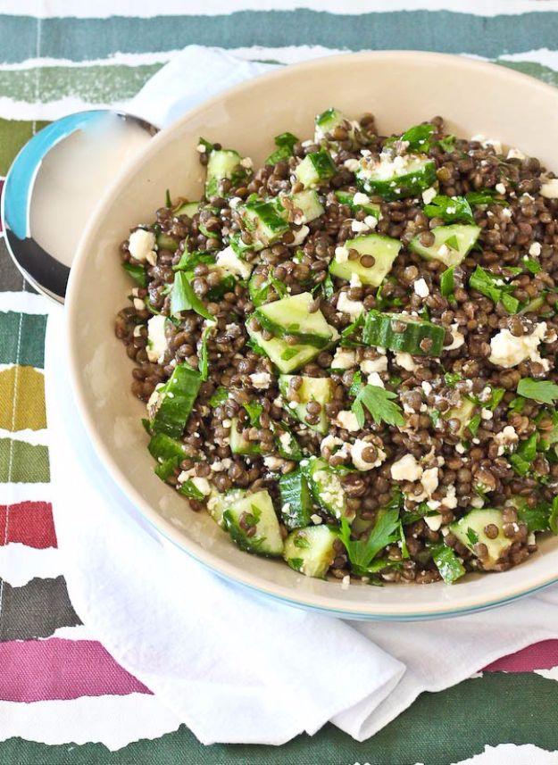 Lentil salad with feta, cucumber and chopped parsley served in a cream bowl on a striped painted background