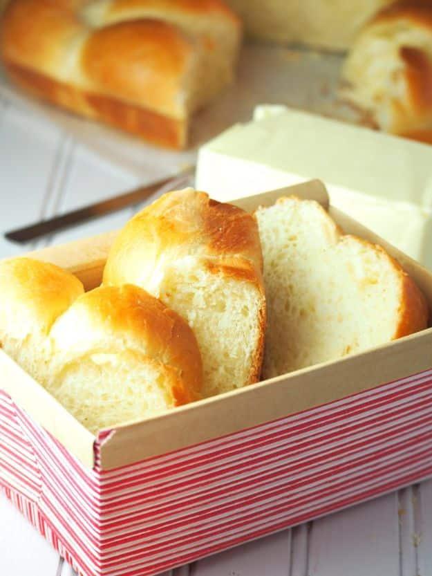 Braided brioche loaf with three glossy golden strands baked together and a fine buttery crumb inside
