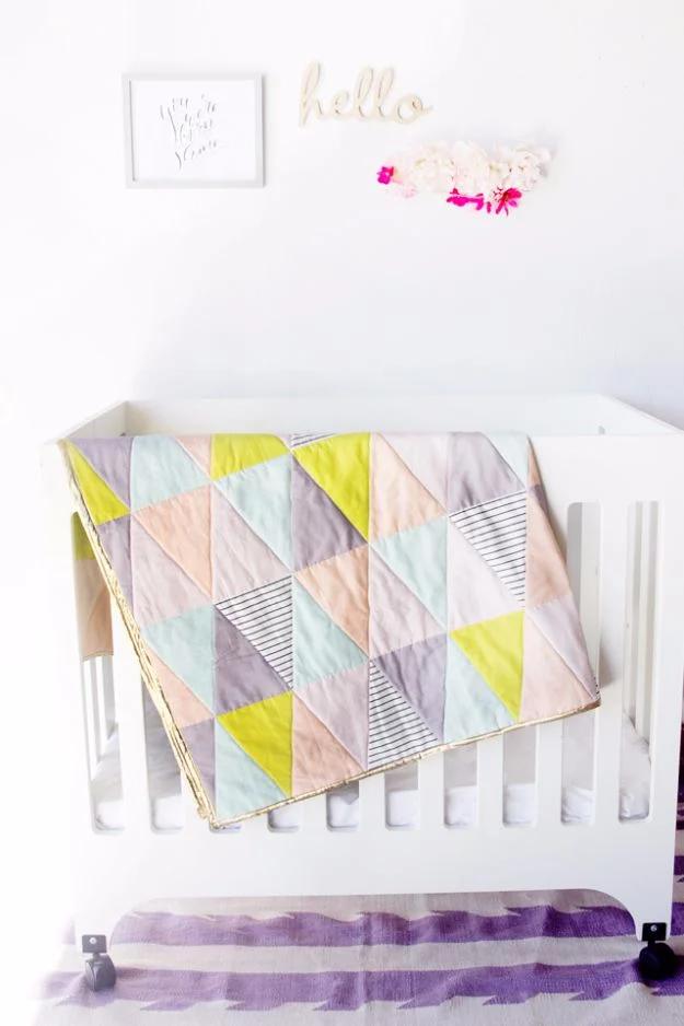 One hour triangle quilt in citron, blush and gray triangles folded over the side of a white crib in a nursery