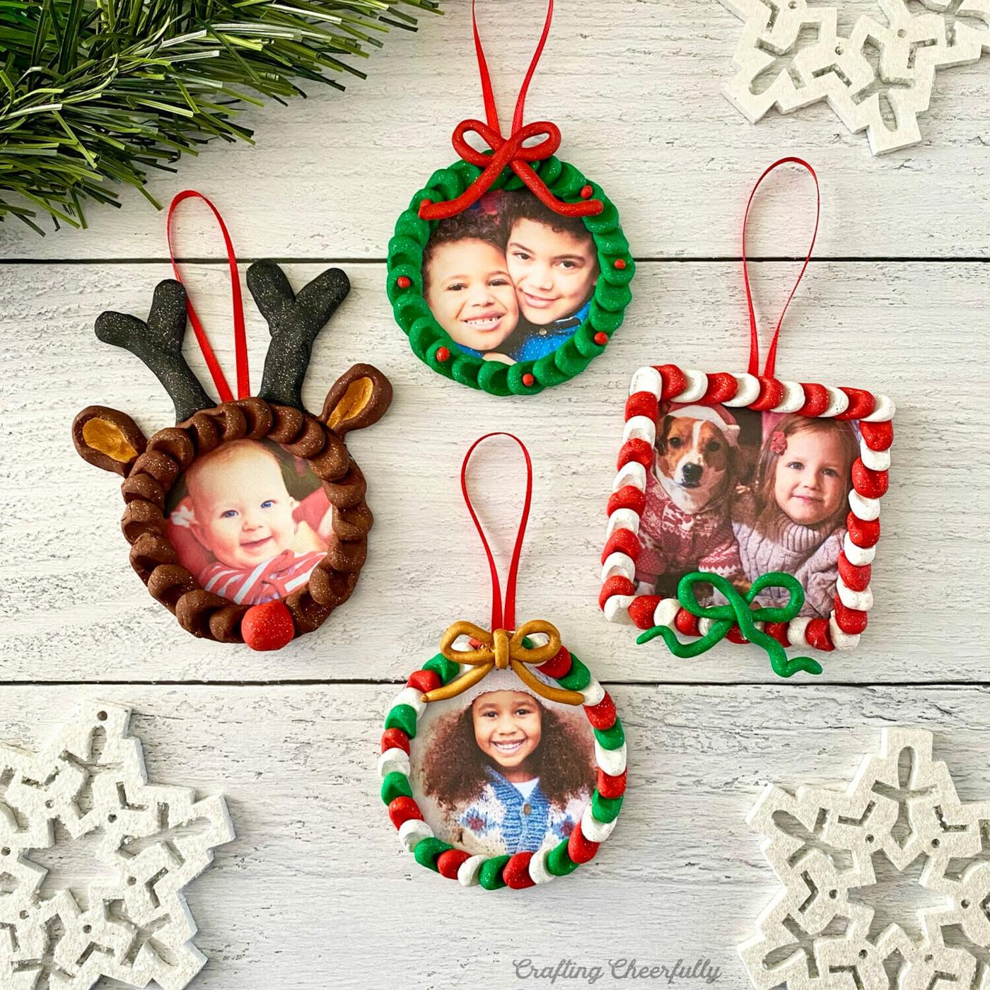 Four clay photo ornaments shaped like a reindeer, a wreath, a candy cane square and a striped ring, each with a kid's photo