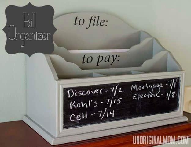 Gray and white wooden desk organizer with to file and to pay labels and a chalkboard front listing handwritten bill dates