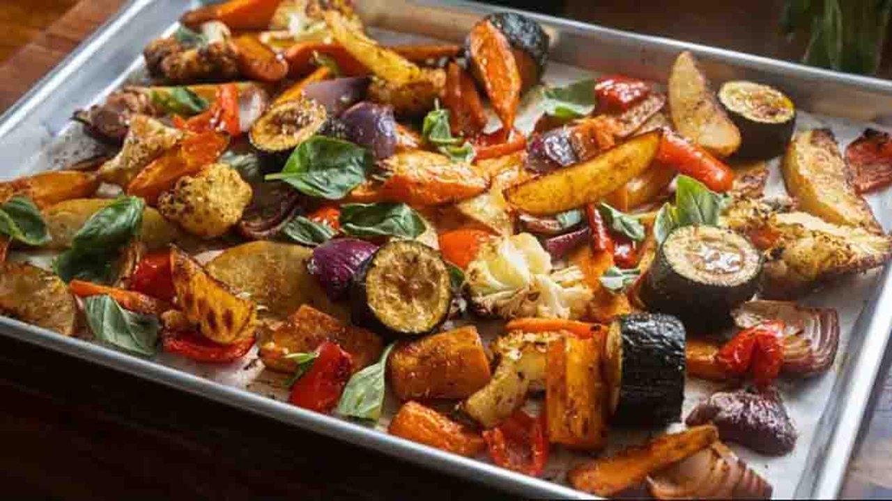One pan roasted vegetables on a sheet pan, peppers, carrots, cauliflower and zucchini with fresh basil