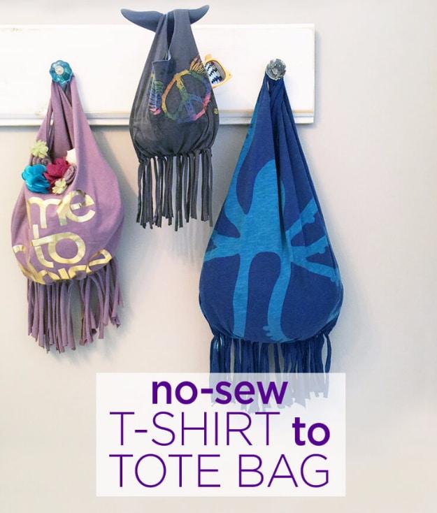 Three totes knotted from old t shirts in purple, charcoal and blue hanging on a peg rail with fringed bottoms