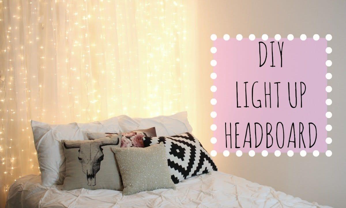 Bed with white bedding in front of a sheer curtain lit from behind by hundreds of warm fairy lights, patterned throw pillows