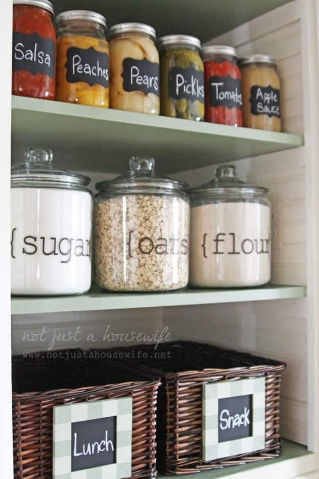 Pantry with mint shelves, labeled canning jars of peaches and pickles, glass canisters and lunch and snack baskets