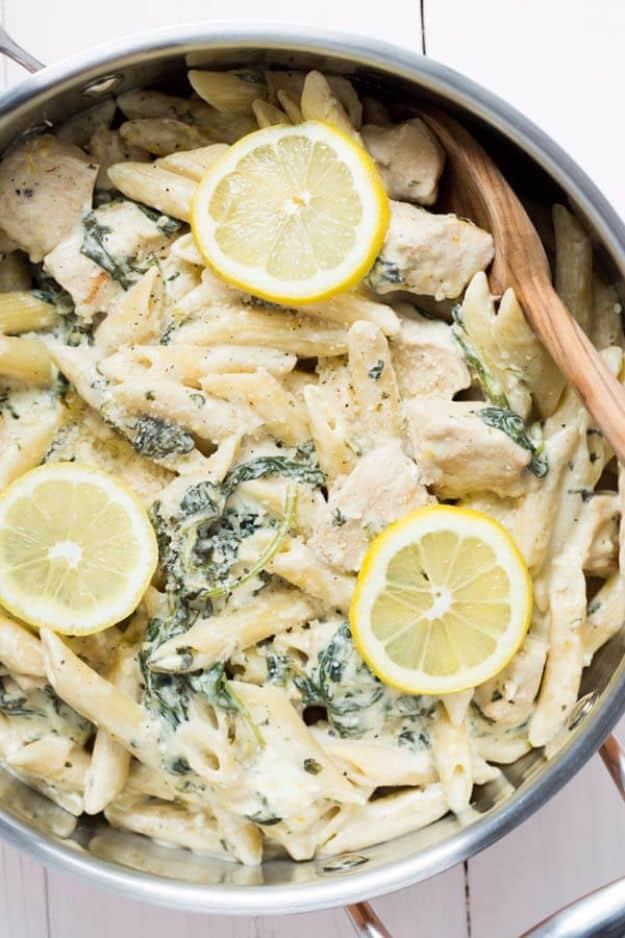 One pot creamy lemon chicken with baby kale, creamy penne and chicken in a steel skillet with lemon slices