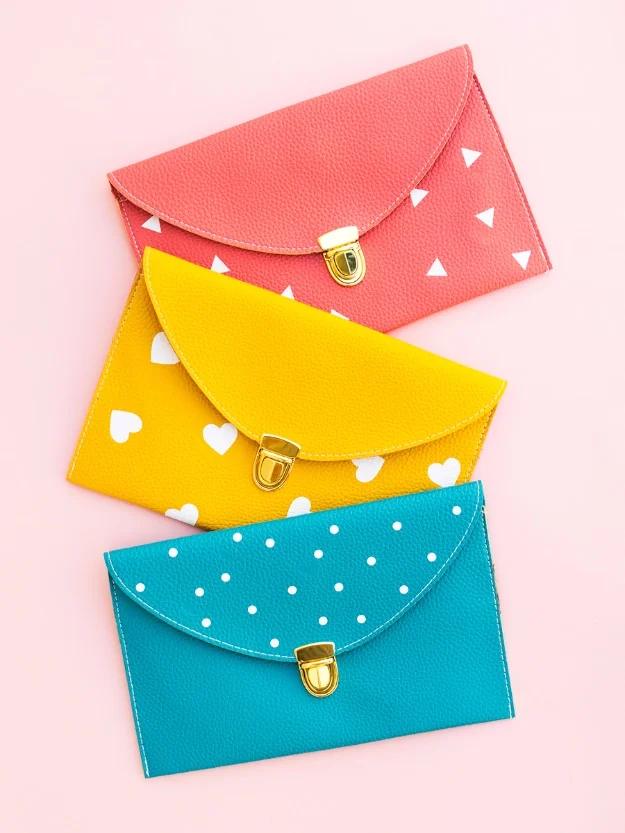 Three pleather envelope clutches in coral, yellow and teal scattered with white triangles, hearts and dots