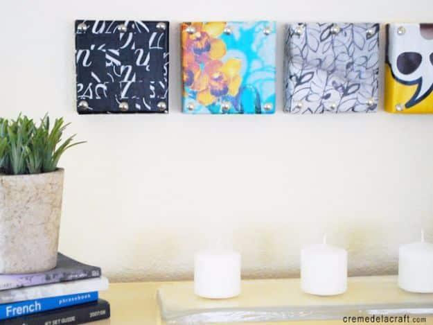 Four small square canvases covered in black and white and floral paper, hung in a row above a white shelf