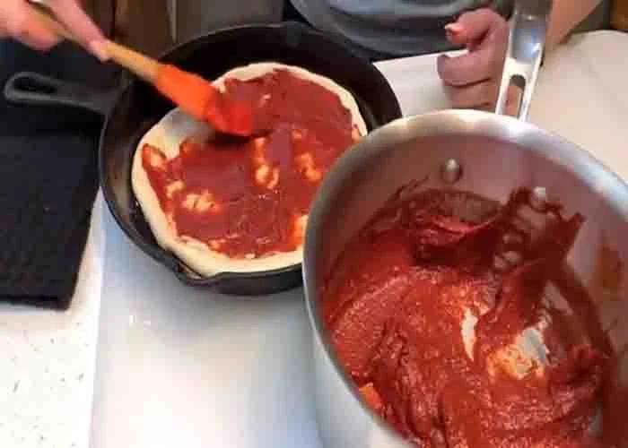 Adding the sauce to the pizza hut copycat recipe