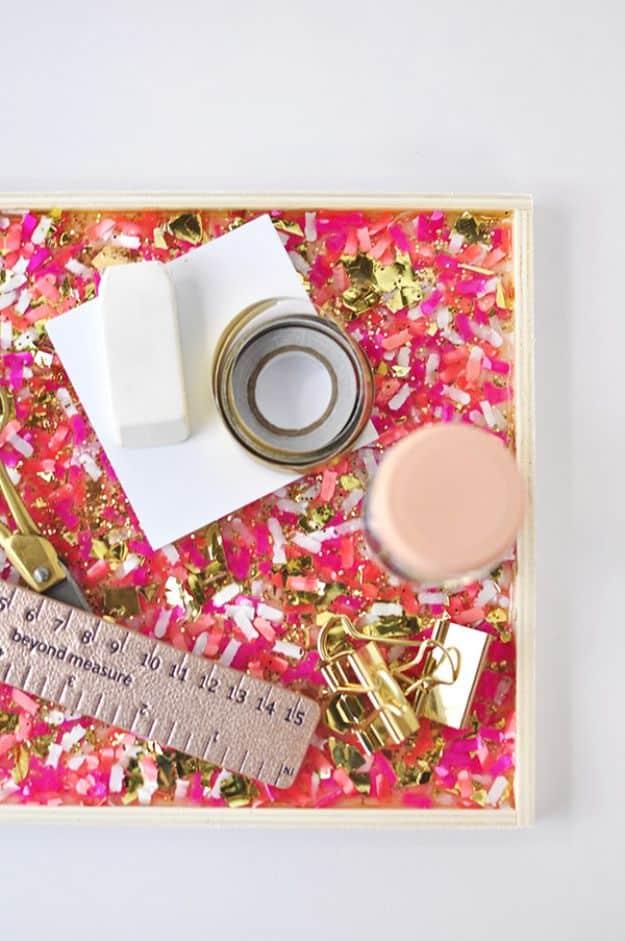 Pink and gold confetti tray holding gold clips, a ruler and a jar lid on a white desk, a beginner decor craft
