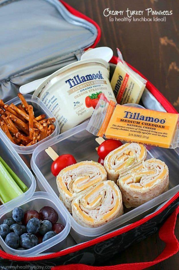 Creamy turkey pinwheels packed in a red lunch box with pretzels, blueberries, celery sticks and cheddar