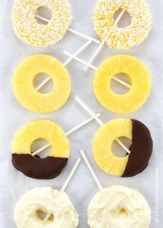 Frozen pineapple ice pops made from tinned pineapple rings on sticks, some dipped in dark chocolate, a tropical snack