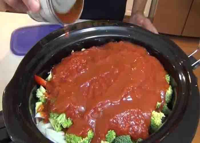 Adding the tomato sauce to the slow cooker chicken and vegetable
