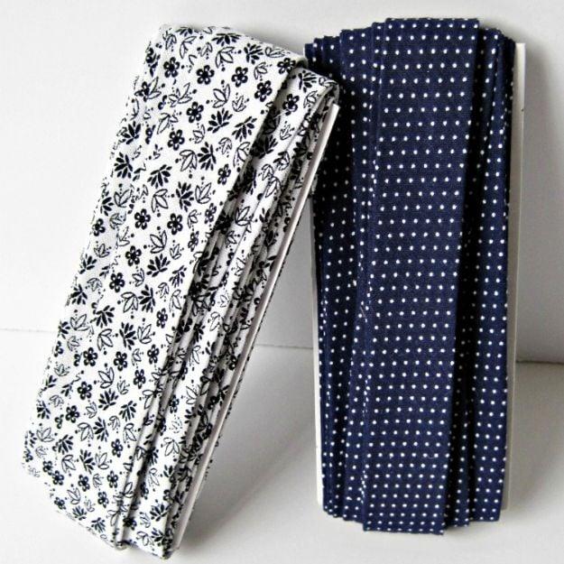 Two lengths of homemade bias tape folded over white blocks, one navy floral and one navy and white pindot