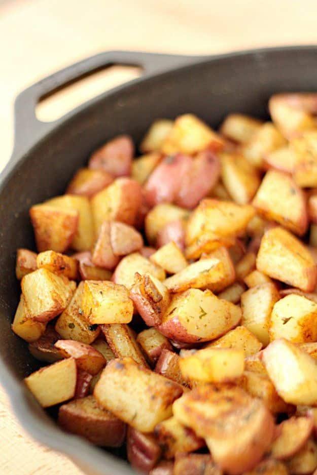 Cast iron skillet filled with browned red potato chunks flecked with paprika and dried parsley flakes