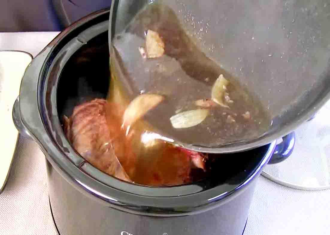 Pouring the beer and beef broth sauce to the beef roast