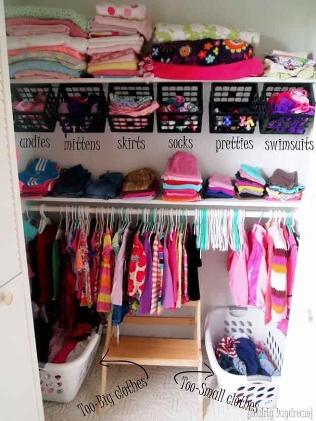 Kids and nursery closet organization, labeled black crates over folded clothes with a hanging rod and two laundry baskets