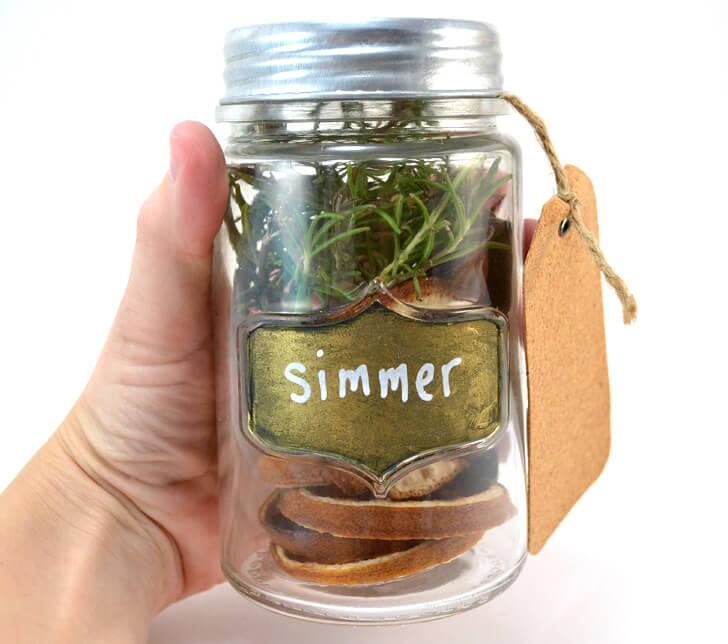 Mason jar packed with dried orange slices, cranberries, cinnamon sticks and cloves for a stove top simmer pot