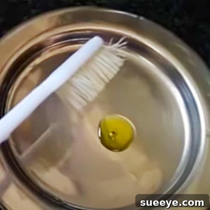 Gold Revival: Simple At-Home Jewelry Cleaning 3 A person gently brushing gold jewelry with a toothbrush and olive oil to remove remaining dirt and enhance shine.