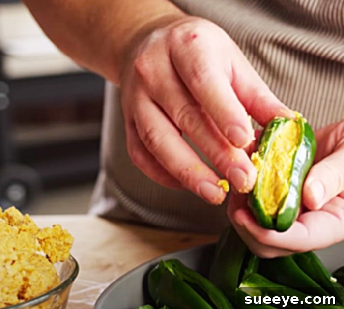 Stuffing jalapenos with cream cheese and cheddar for bacon-wrapped chicken poppers