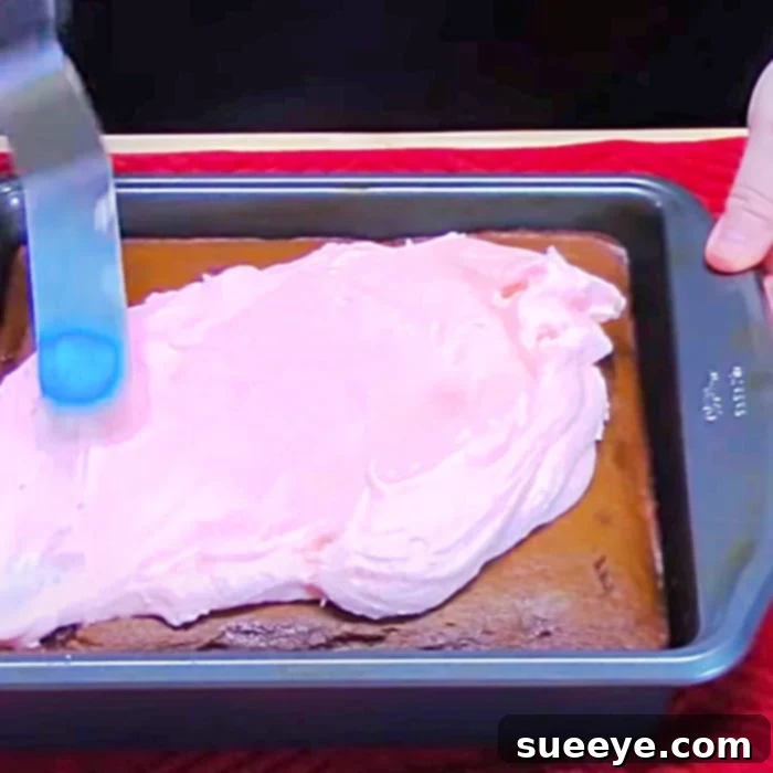 Cherry Coke Poke Cake Delight 3 Cherry frosting being spread over a freshly baked poke cake