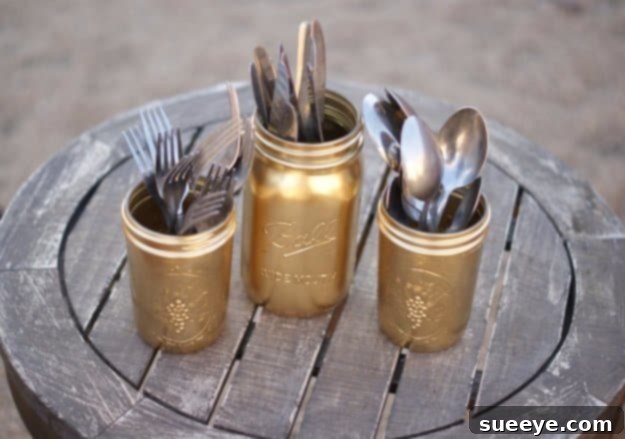 DIY Gold Painted Mason Jars for Silverware Storage Mason jars with gold-painted exteriors, holding silverware as a decorative organizer