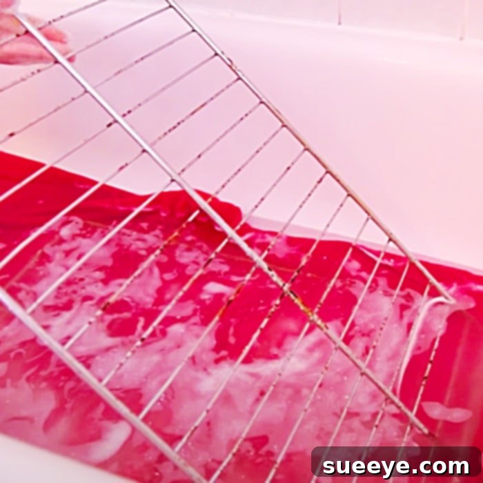 Unlock The Secret To Clean Oven Racks 3 Oven racks soaking in bathtub with hot water and laundry detergent