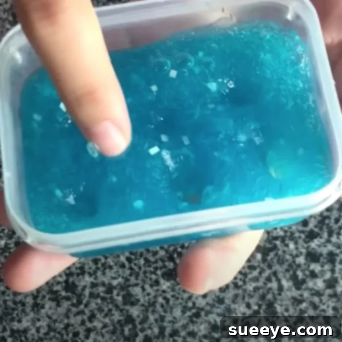Minty Slime Made Without Glue 2 A person's hand holding a green toothpaste slime, demonstrating its sticky and pliable texture, ready for cleaning.
