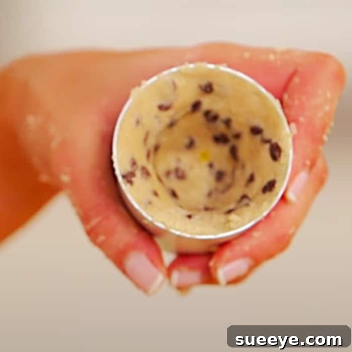 Cookie dough being pressed into shot glass molds